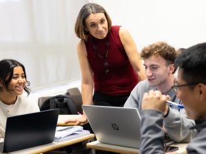 A teacher interacting with smiling students in a classroom setting.