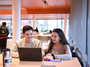 A male and female Adelphi University student studying on a laptop computer in the Nexus Building