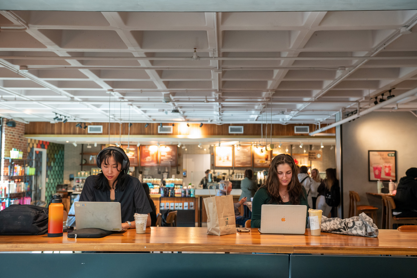 Two students sit at a table, working on their laptop computers, in the University Center Starbucks.