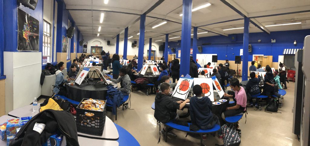 a group of students painting artwork of basketballs together