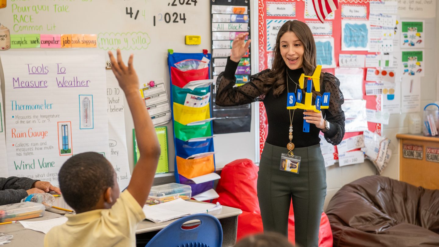 An education student lading a classroom of children in a lesson about direction.