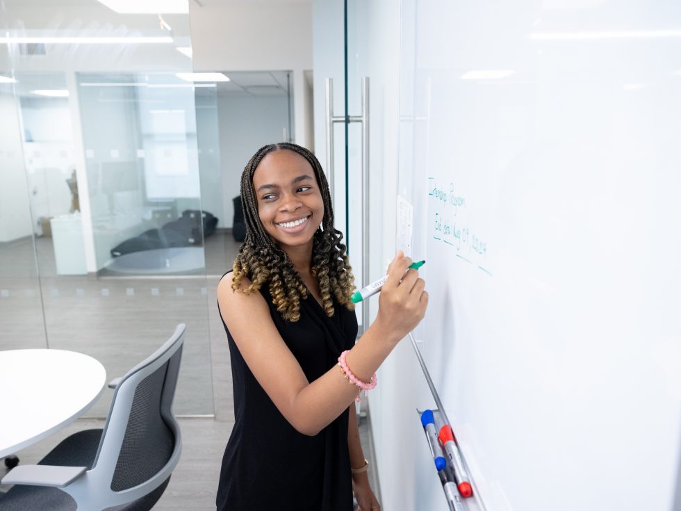 Adelphi social work student smiling while writing at a whiteboard.
