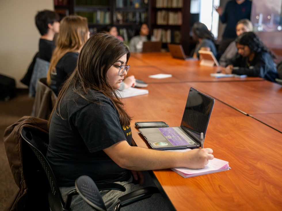 Honors College student at Adelphi University taking notes during a seminar.