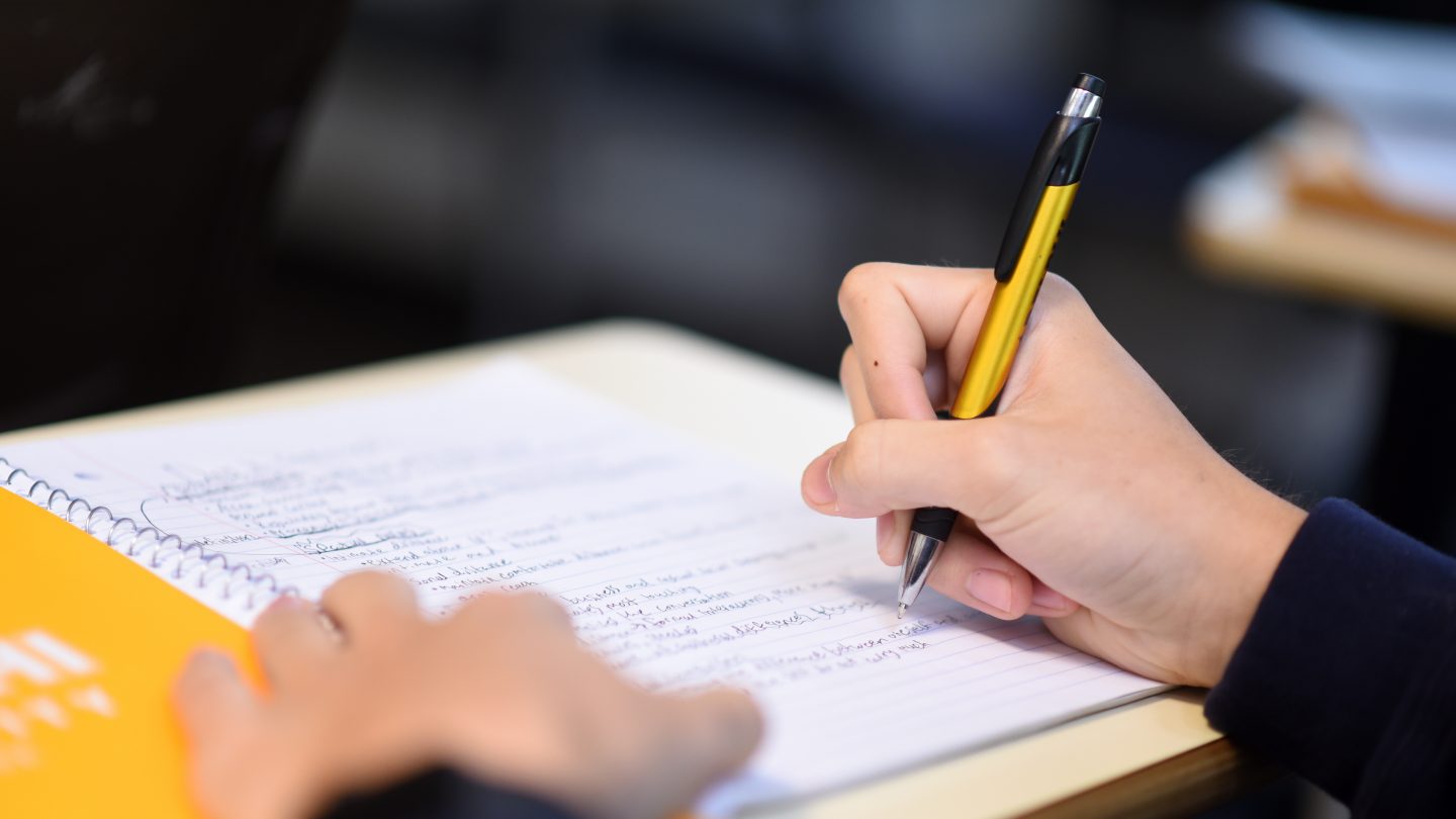 Close up of student writing notes in class