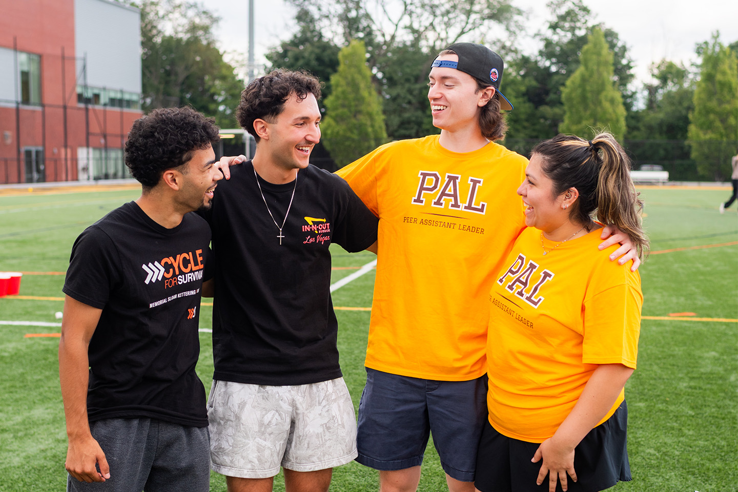 The current PALs, in yellow shirts, talk with the two alums, who are wearing black shirts.