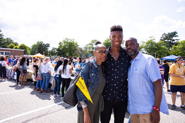 a student hugs his parents on Adelphi's campus