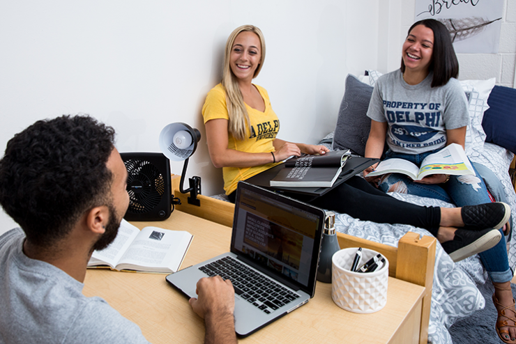 Friends at Adelphi using laptops in their dorm room