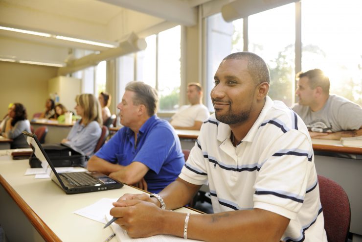 A look inside the classroom at Adelphi. A student smiles wile sunshine pours in the window.