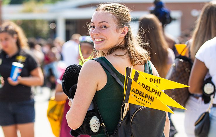 A student at a social event on campus with Adelphi University flags in her backpack