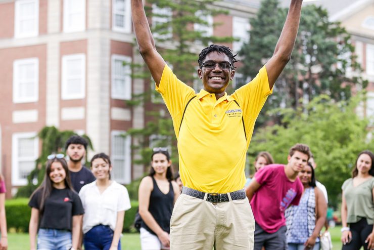 Adelphi orientation leader smiling with arms outstretched. Welcome!