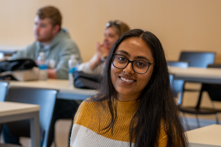 A beautiful student in a classroom looking at the camera