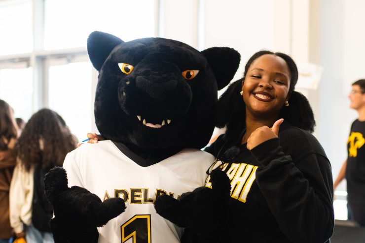 Adelphi first-year student poses with thumbs up with Adelphi Panther mascot.