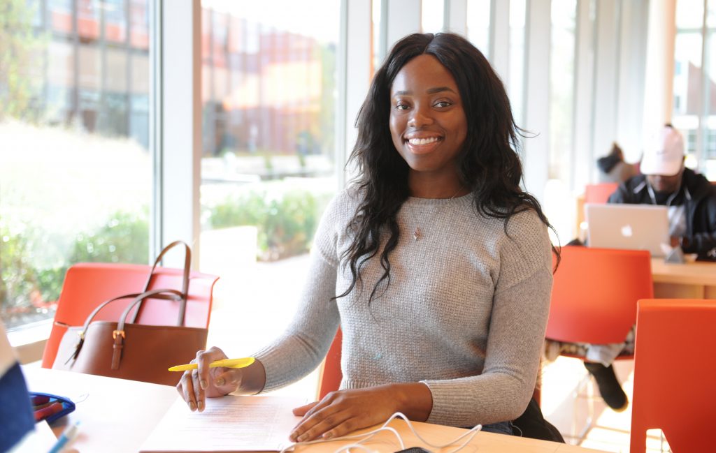 Adelphi student smiles while studying in the Nexus Building.