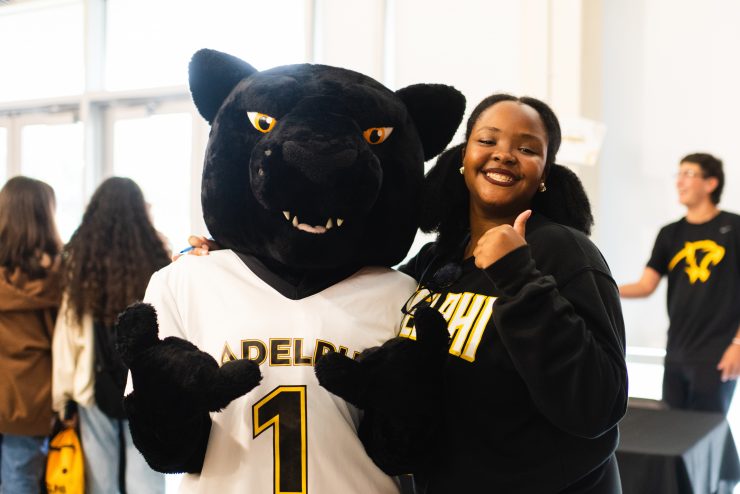 The Adelphi mascot, Paws the Panther, poses with a student