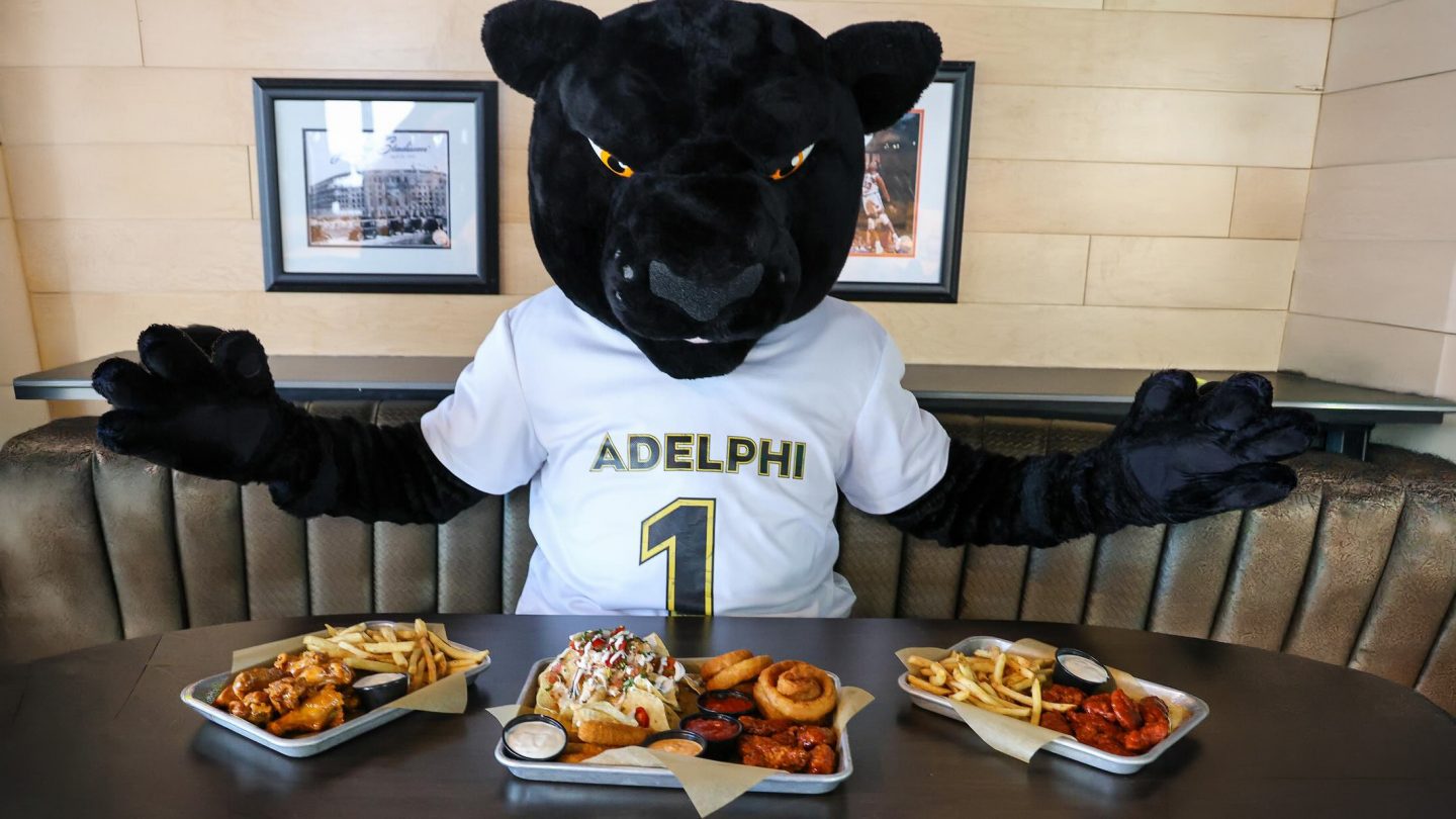 Adelphi Panther mascot sitting down to a meal at a local business with a discount.