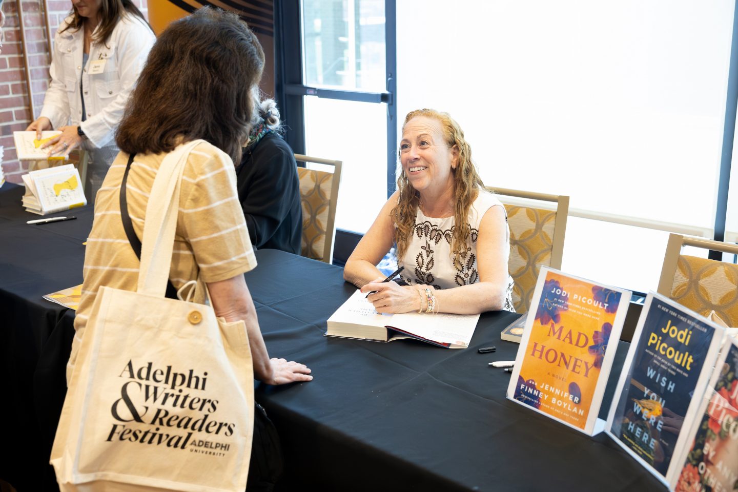 Jodi Picoult signs a copy of her 2024 novel, By Any Other Name, for one of her many readers.