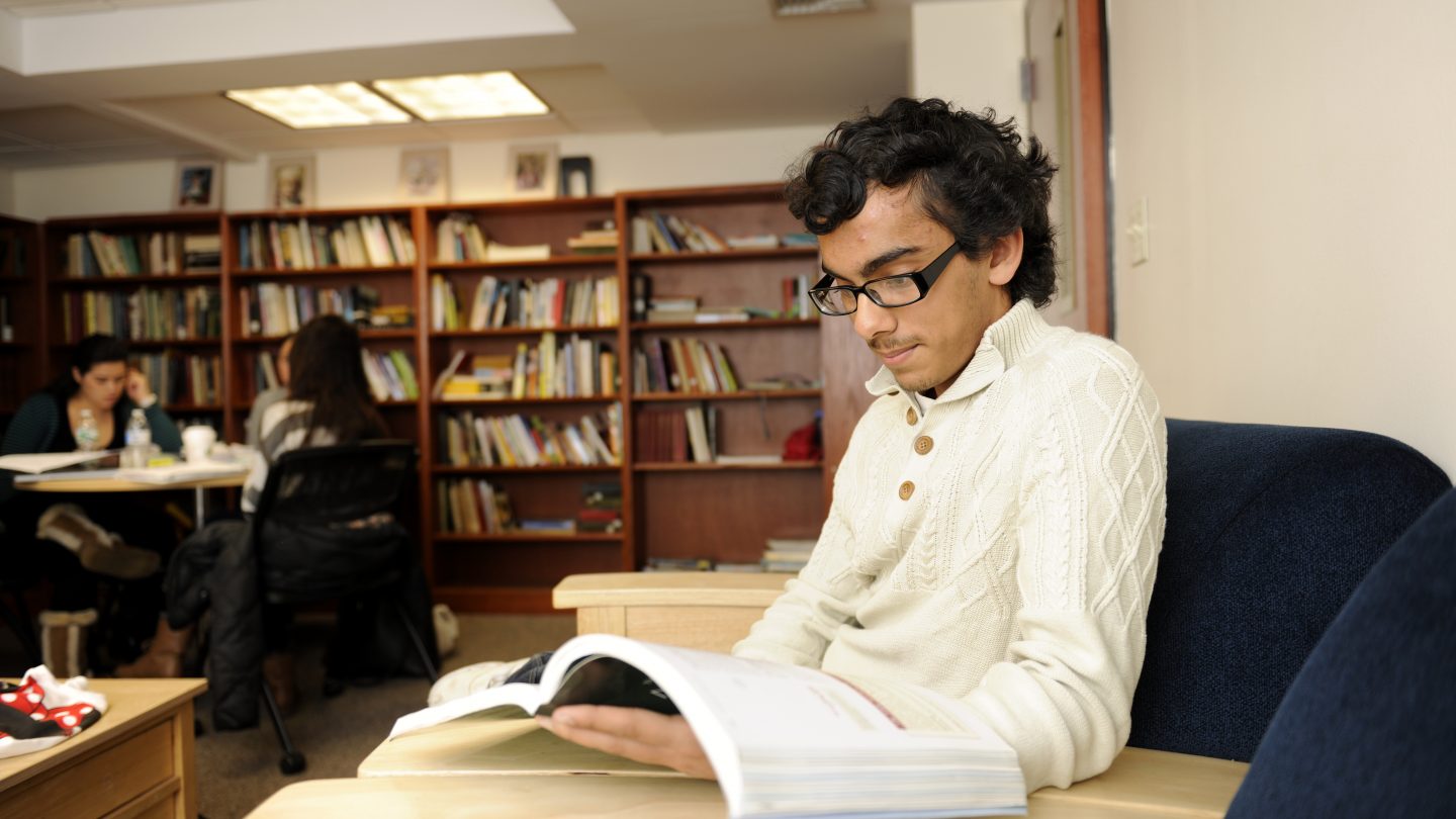 Student reading a textbook at Adelphi University.