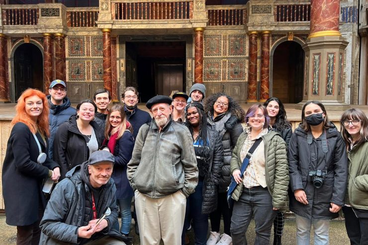 Lead by Brian Rose, Adelphi students studying theatre acting with a design and technology pose in front of the stage at Shakespeare’s Globe Theatre in London.