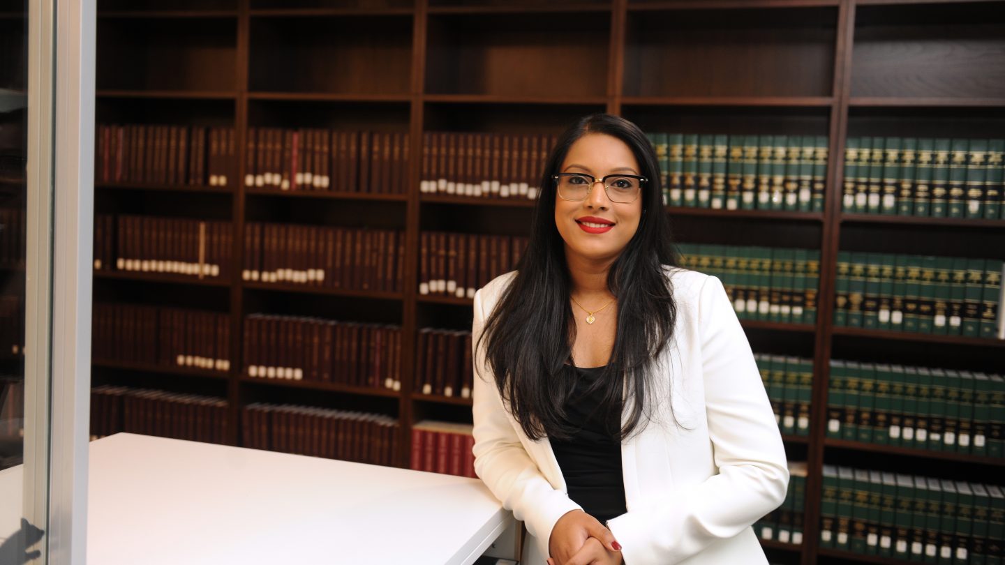Dilara Islam standing in front of bookshelf.
