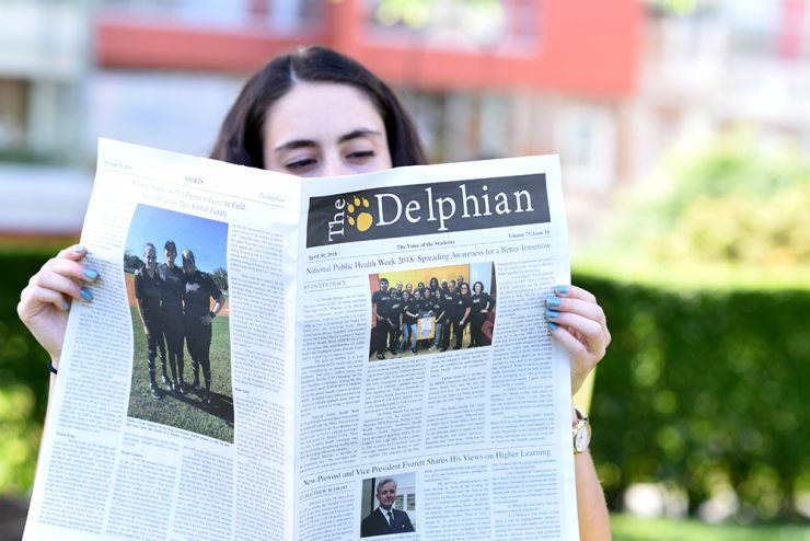 Student reading the Delphian newspaper