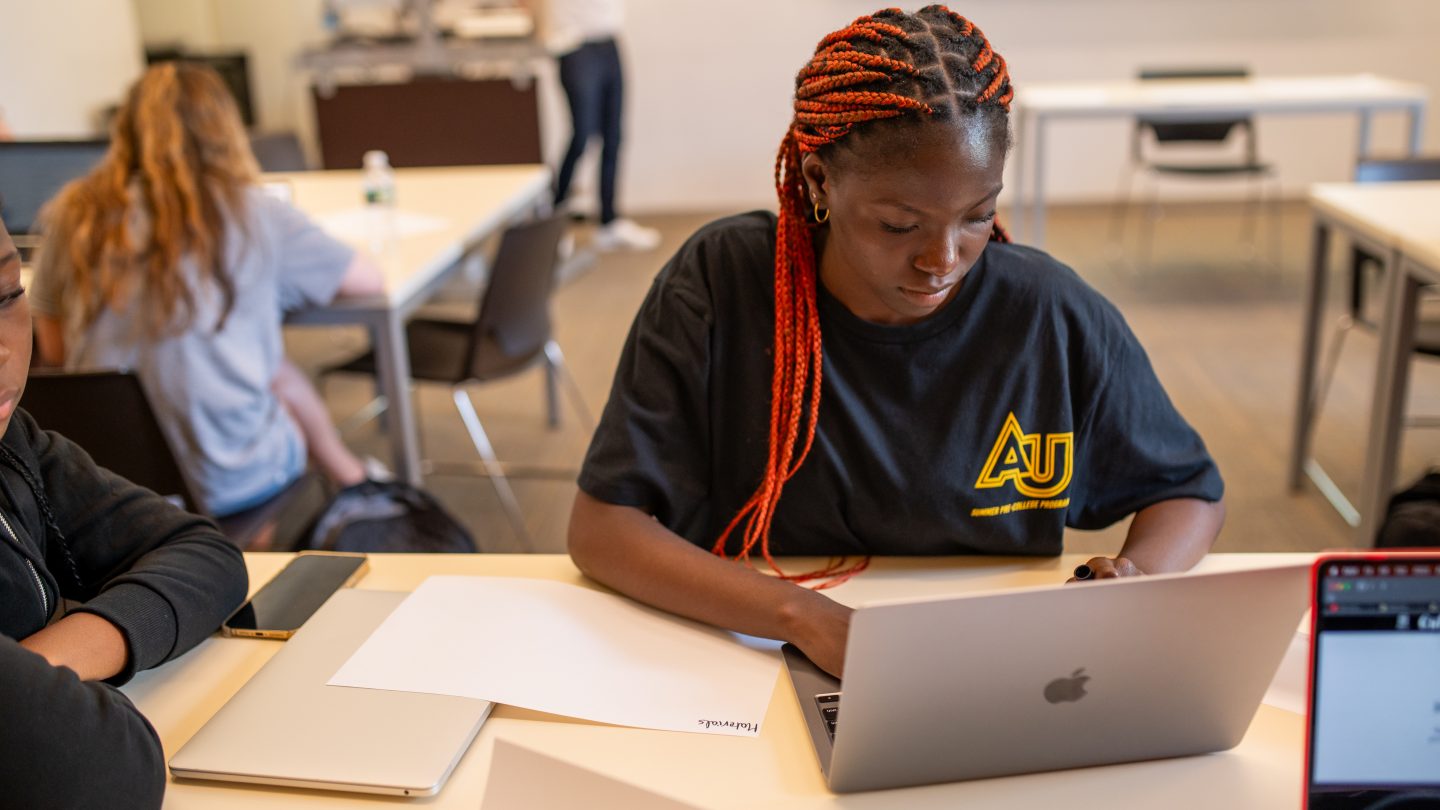 A student in Adelphi’s pre-college Communication and Critical Thinking course listens to a lecture with a laptop open in class.