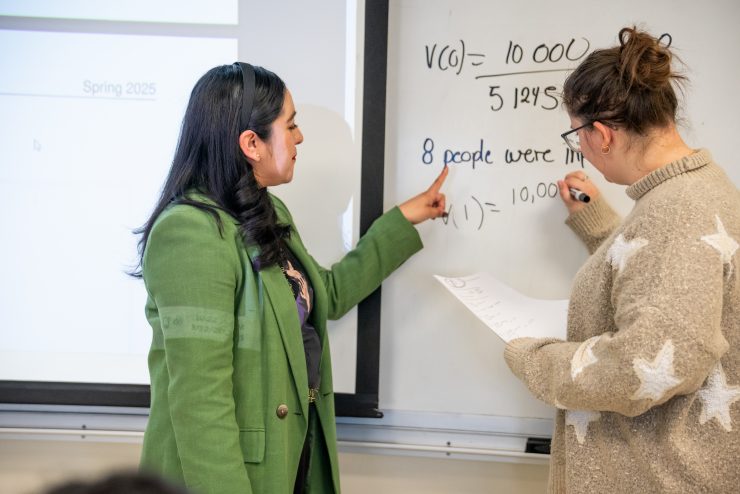Professor Monica Morales-Hernandez working through an equation in class with an Adelphi student.