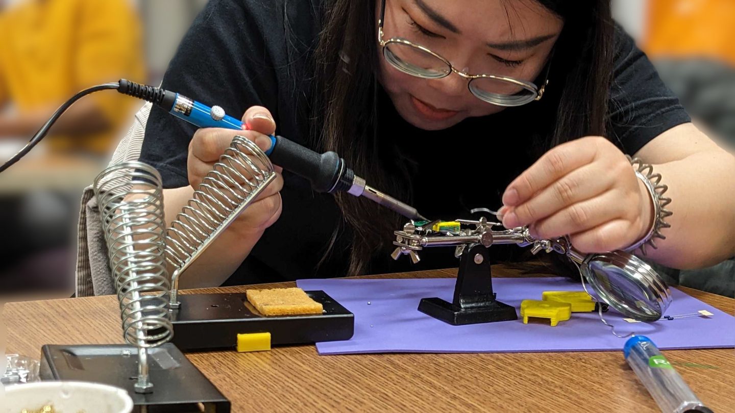 Adelphi student soldering during class.