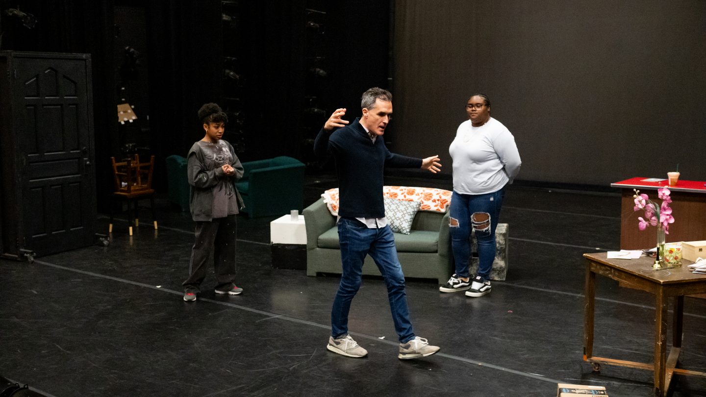 Acting professor Tommy Schrider on a theatre stage working with an Adelphi student hands-on.