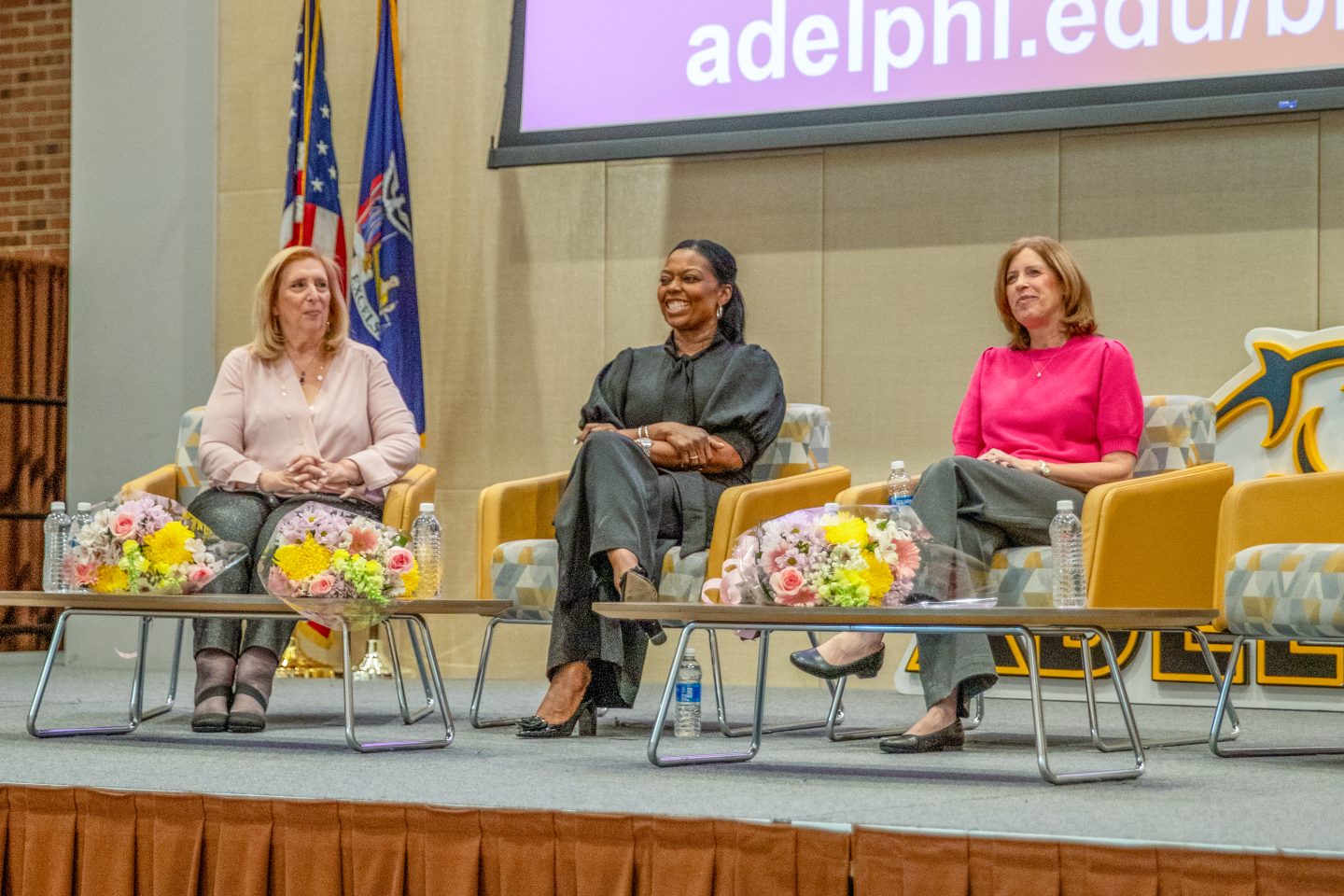 Three women sitting in chairs on stage