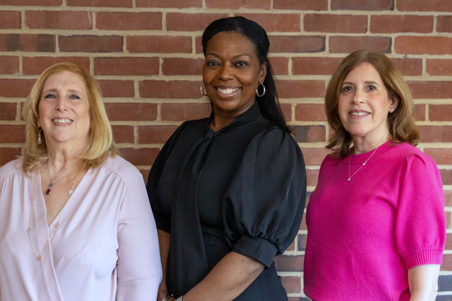 three women in front of a brick wall