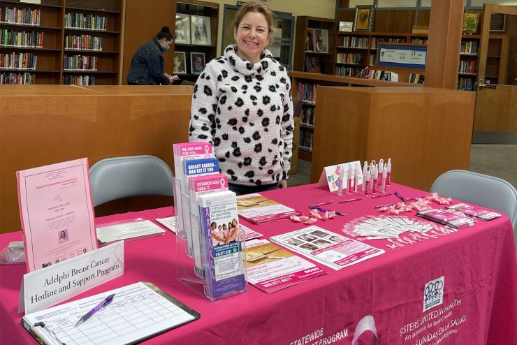 Sandra Martinez, Bilingual Outreach Coordinator for the Adelphi NY Statewide Breast Cancer Program standing behind an educational outreach table.