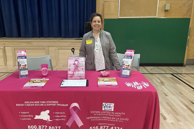 Sandra Martinez, Bilingual Outreach Coordinator for the Adelphi NY Statewide Breast Cancer Program standing behind an educational outreach table.
