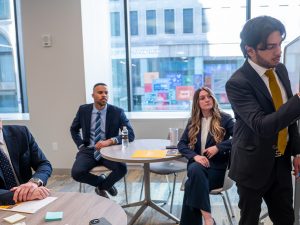 Four individuals in business attire collaborating on a presentation in a modern work space