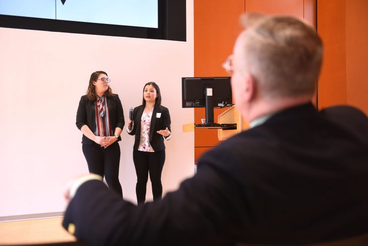Two students pitch their business idea to judges in order to win seed money