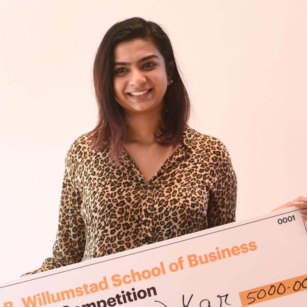 Adelphi student Pooja Kar holding a check after winning the Business Plan Competition.