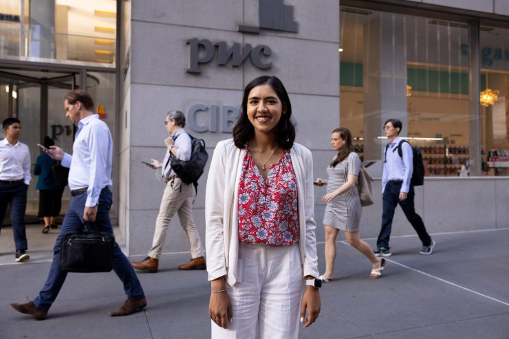 Adelphi student Sarah Baksh stands in NYC with arms crossed wearing a suit. She secured an internship with PWC.