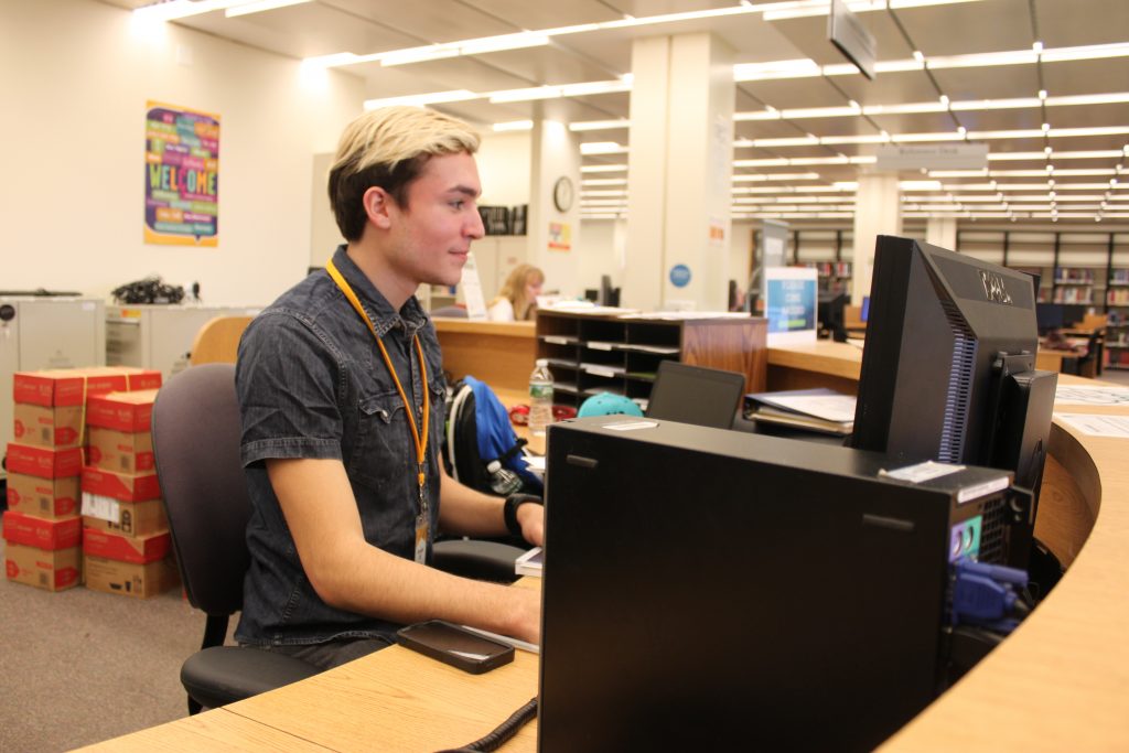 An Adelphi student working at the IT Help Desk in Swirbul Library.