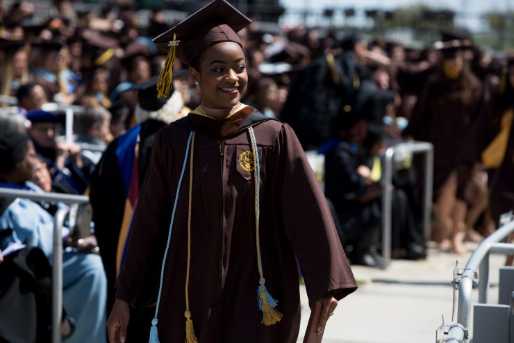 An Adelphi graduate wearing their brown cap and robes.