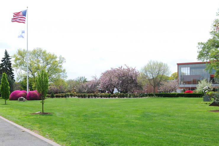 Flagpole Lawn at Adelphi is an open green space full of flowers and trees.