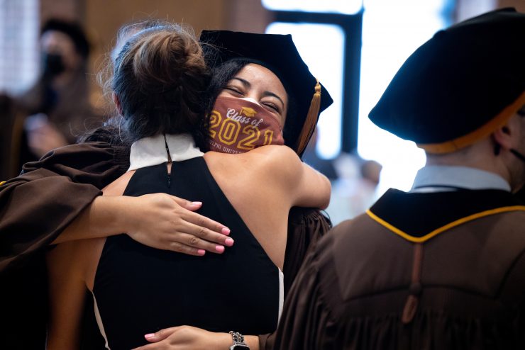 An Adelphi doctoral candidate hugs their loved one wearing a "Class of 2021" mask