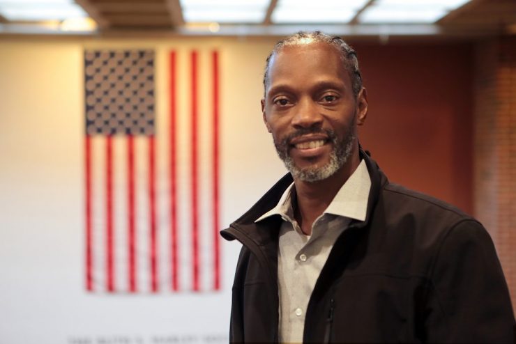 Veteran Brent Russell at Adelphi University standing in front of an American flag