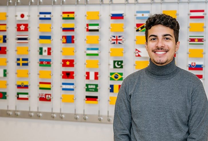 Caio Gomes standing in front on the UC international flags