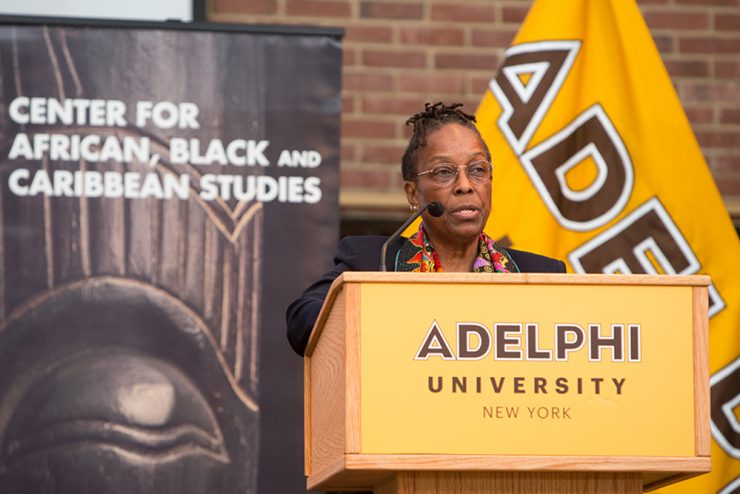 Marsha Darling speaking at a podium in front of a sign for the Center for African, Black and Caribbean Studies