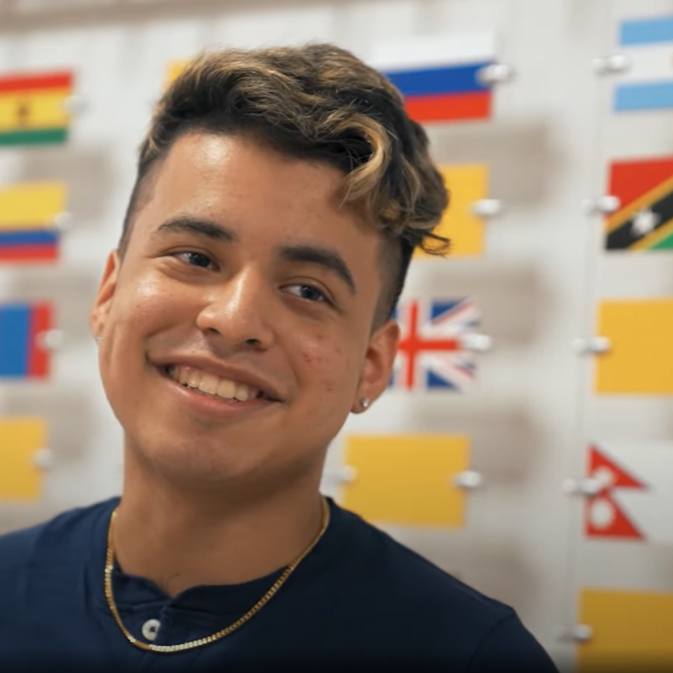 Jason Menjivar standing in front of a wall of international flags