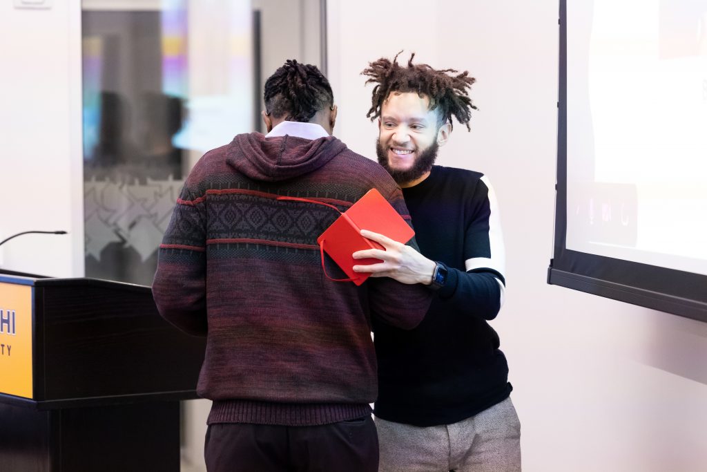 Adelphi student hugs their mentor during an event on campus.