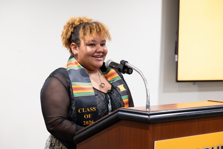 Adelphi student wearing graduation stole for African Studies program. Confident and speaking at a podium.