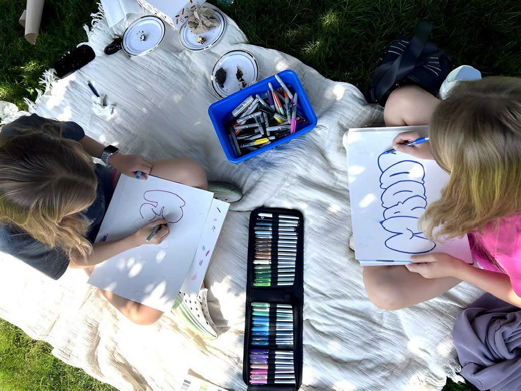 two children draw outside at Adelphi's art camp.