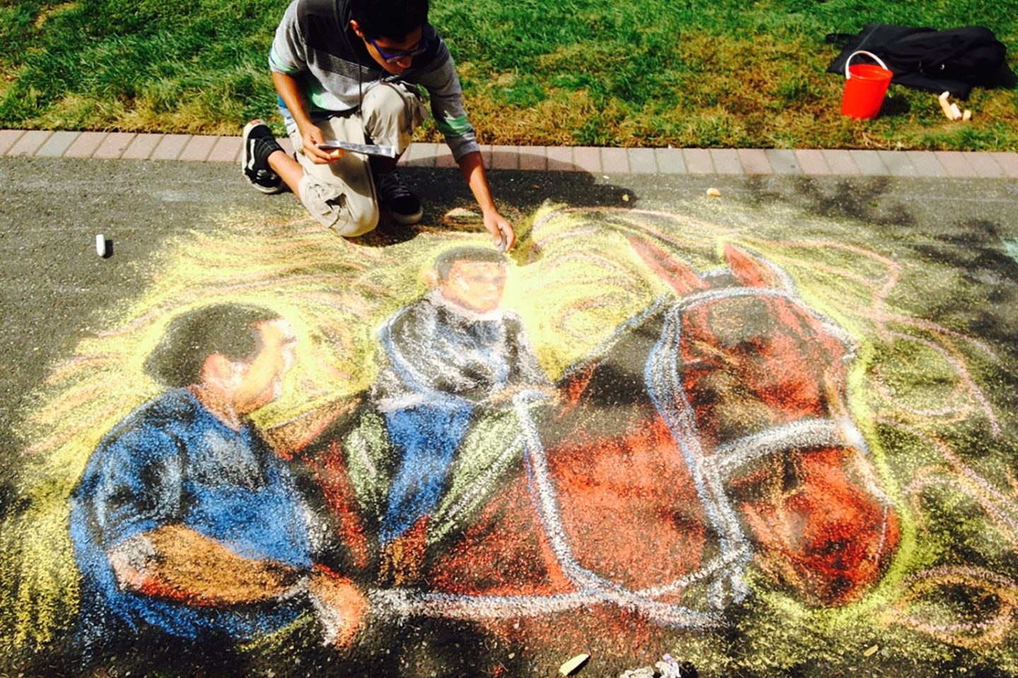 Adelphi student drawing a horse and rider chalk design for the 2021 Fall Arts Festival.
