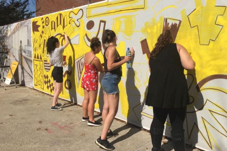 Adelphi student draws butterflies on the sidewalk during Fall Arts Festival.