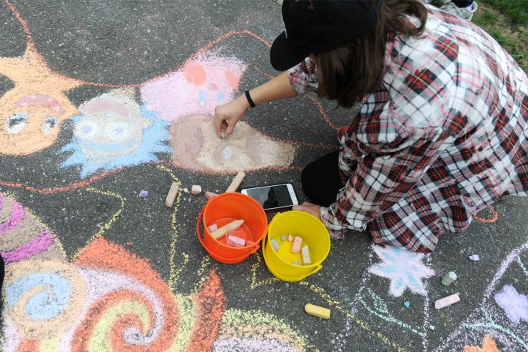 Adelphi student draws butterflies on the sidewalk during Fall Arts Festival.